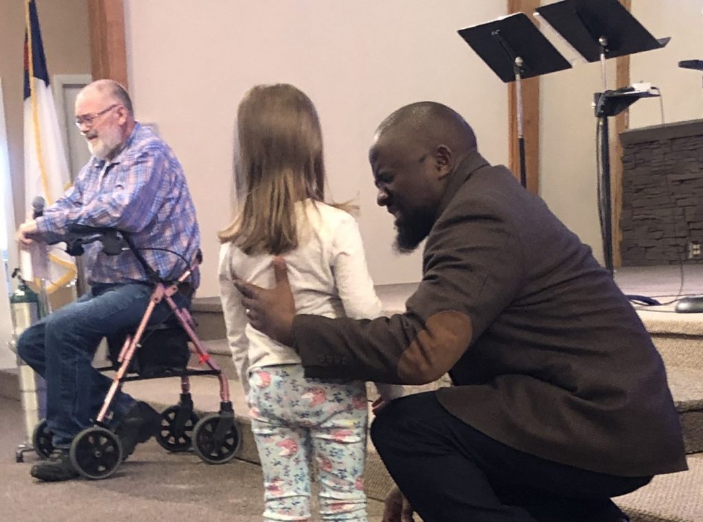 Pastor prays with young girl after hearing testimony